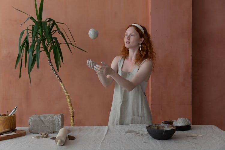 Young Woman Throwing Ball Of Clay In Pottery