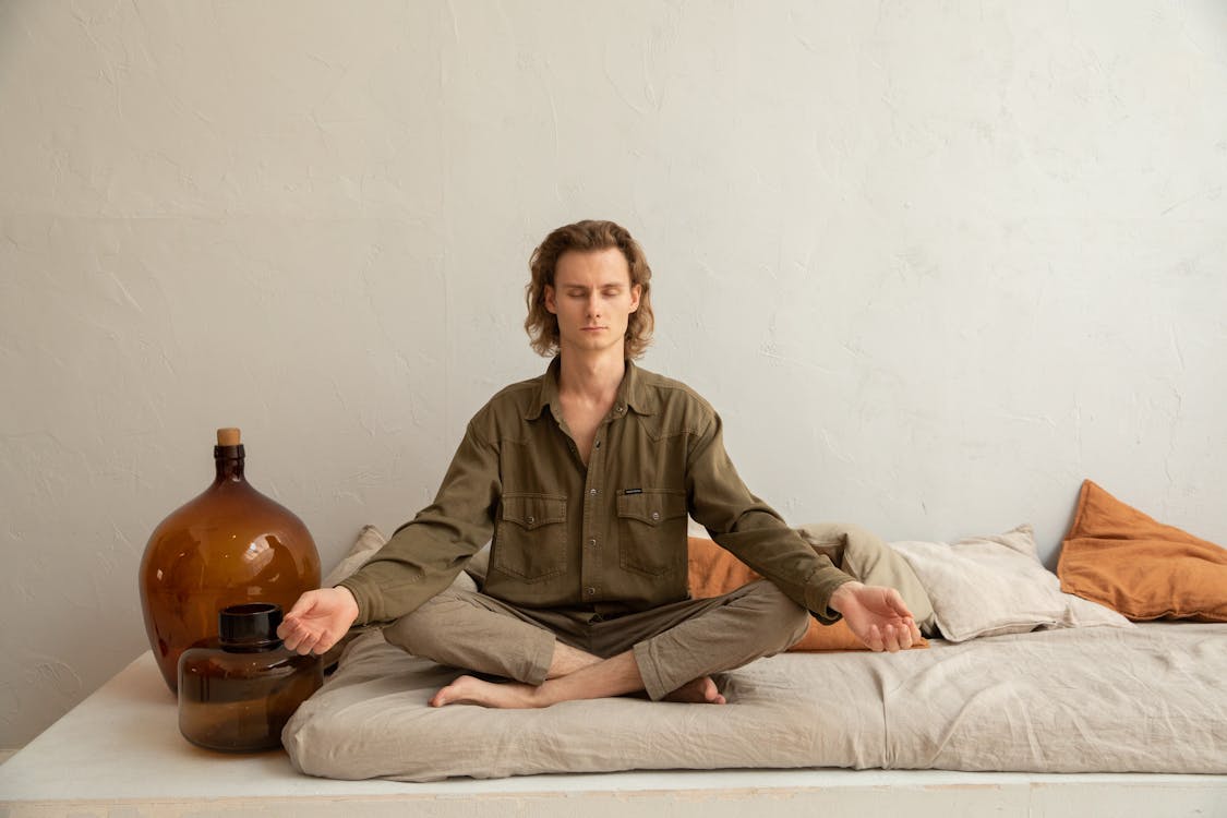 Serene man meditating in Lotus Pose on sofa