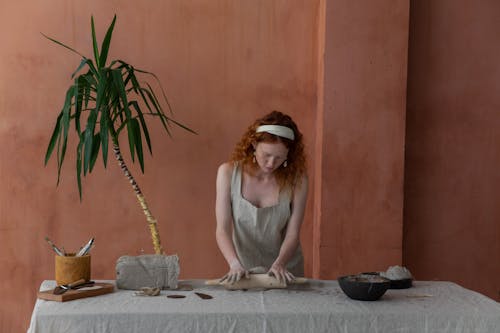 Concentrated craftswoman rolling out clay slab in workshop