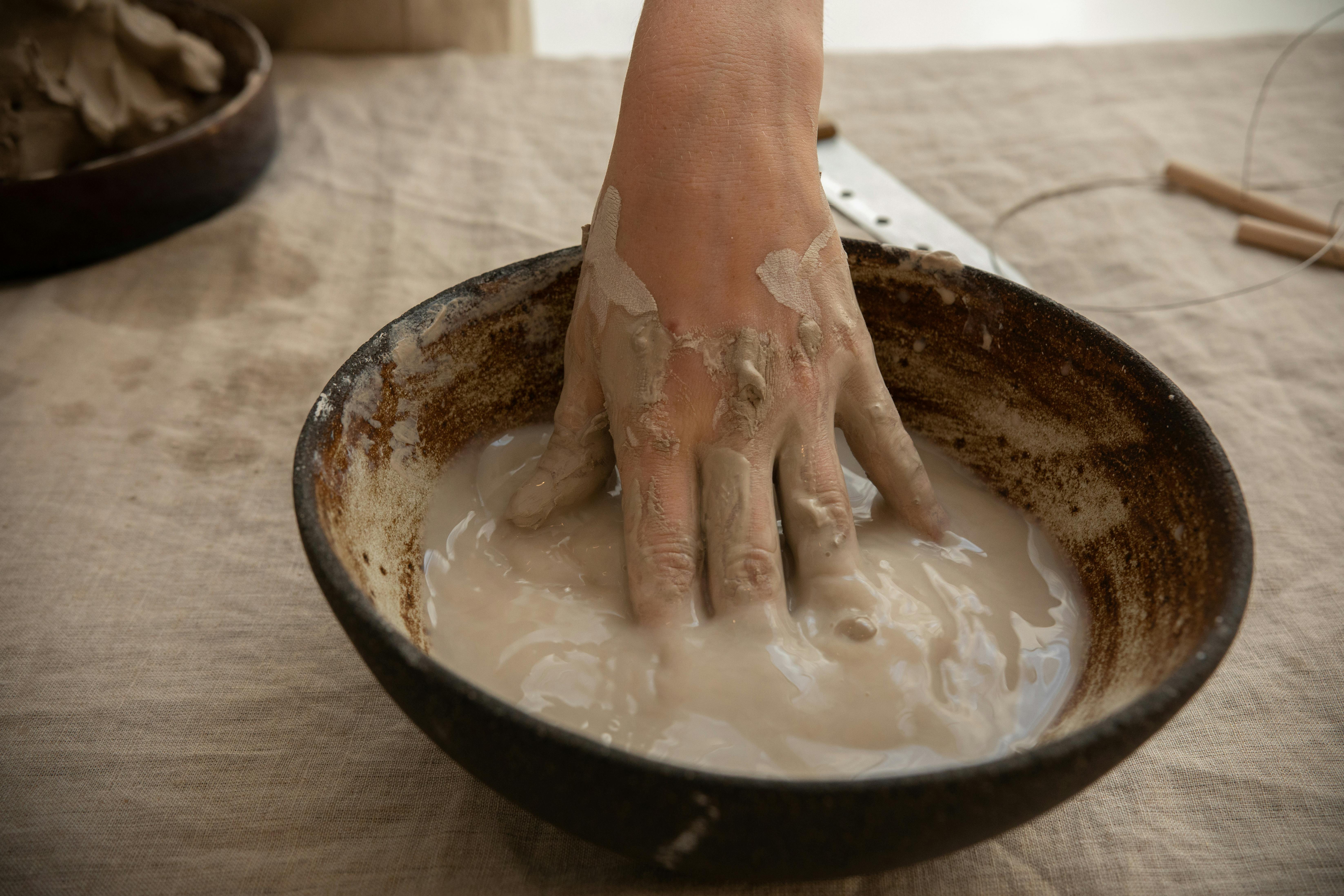 crop ceramist with hand in clay