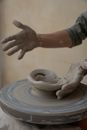 Crop man modelling clay bowl on wheel