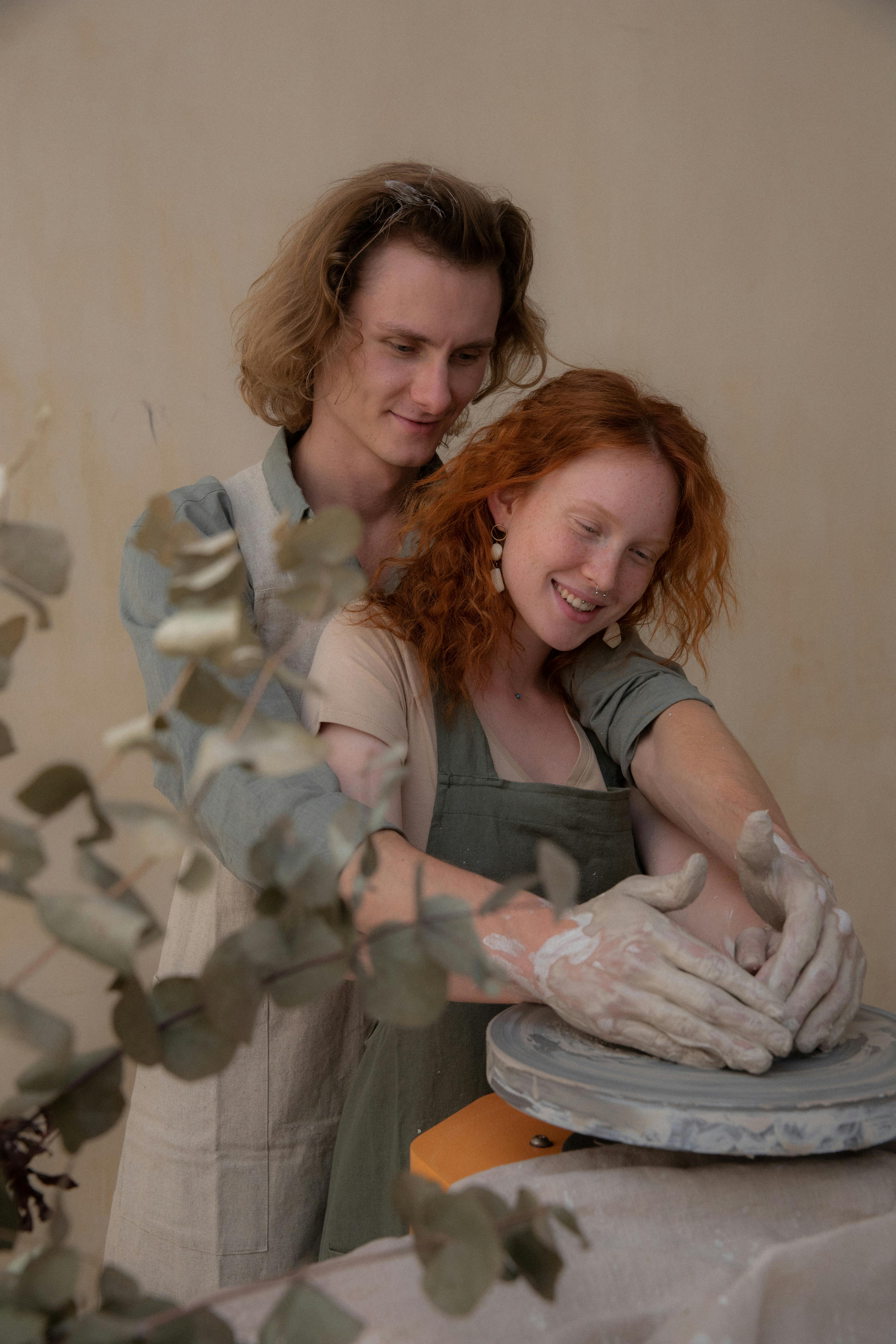 happy couple creating clay pots while hugging