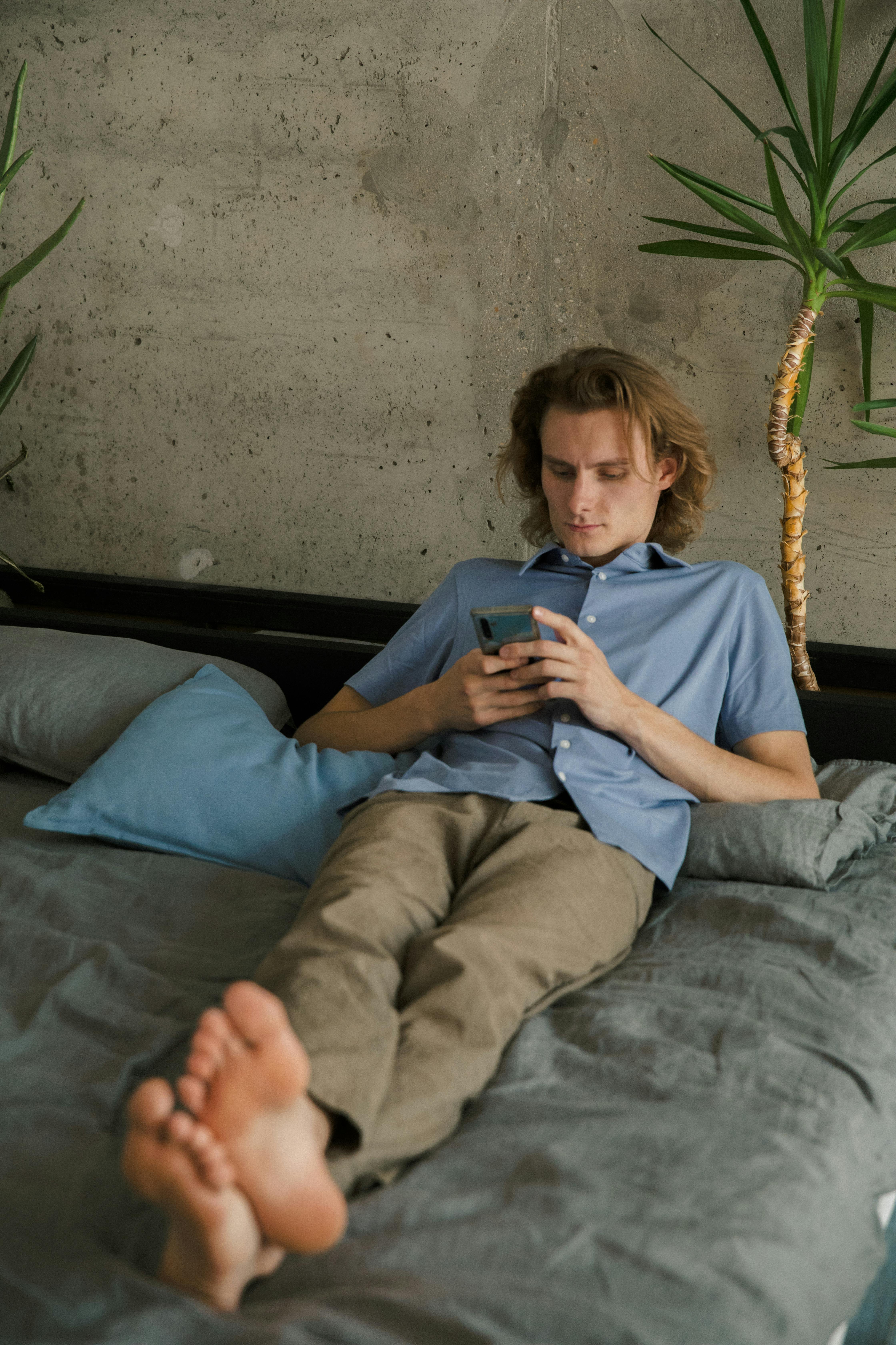 young man browsing smartphone on bed