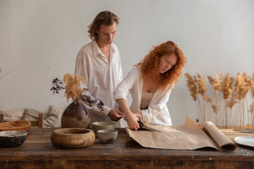 Busy woman cutting craft paper during work with partner