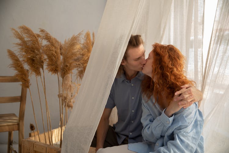 Loving Couple Kissing Near Curtain