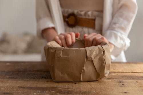 Free Crop woman packing bowl with paper Stock Photo