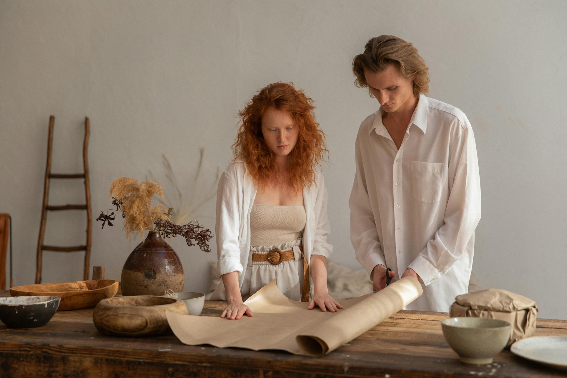 Couple in a creative workspace wrapping an item with focus and style.