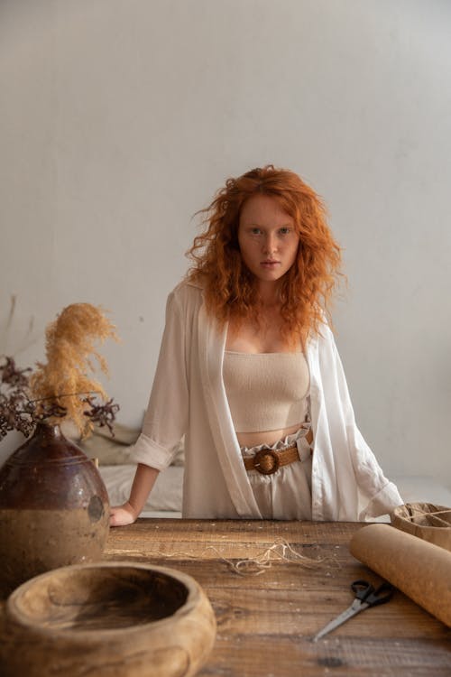 Ginger woman standing near wooden table