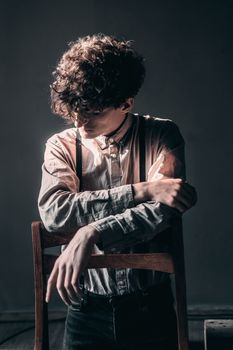 一位穿着休闲服、棕色卷发的匿名男子站在木桌旁向下看