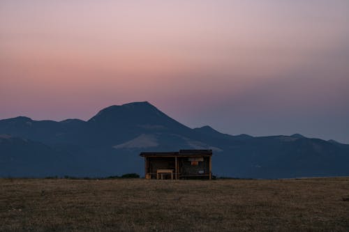 Solitary Building in Meadow with Mountain in Distance 