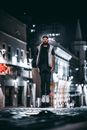 Man in Black Jacket and Black Pants Standing on Street during Nighttime