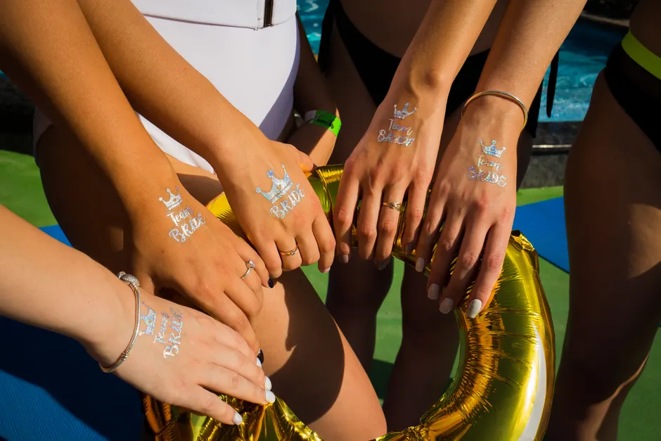Groupe d'amis à la plage affichant leurs tatouages temporaires significatifs et colorés.