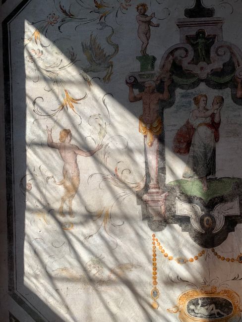 Sunlight cast on intricate Renaissance frescoes in a Lombardy church.