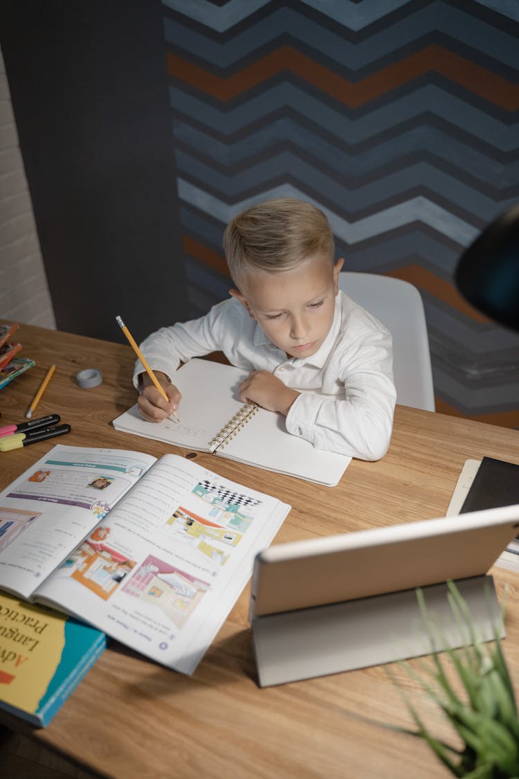 A Boy Looking At A Tablet While Studying 