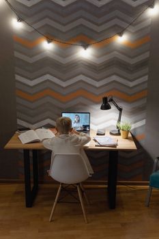 A young boy engaging in an online class at his desk, studying diligently at home.