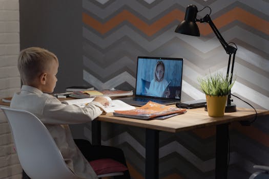A young boy focused on a virtual class at his home desk, embracing modern education technology.