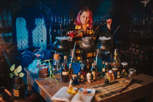 Free A woman in a magical lab creates potions with cauldrons, bottles, and spellbooks. Stock Photo