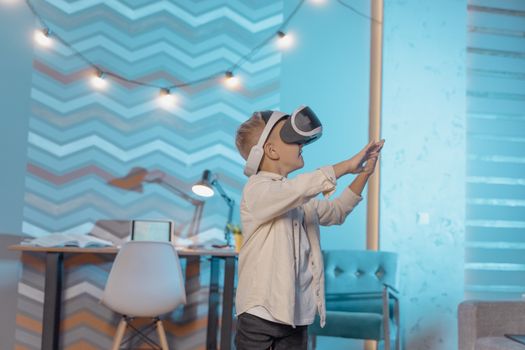 Young boy wearing VR headset, immersed in virtual reality in cozy indoor setting.