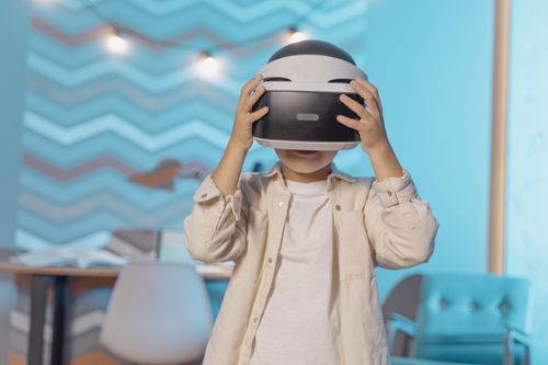 Free Young boy exploring virtual reality with VR goggles indoors, enjoying technology in a cozy setting. Stock Photo