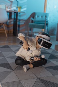 A young boy sitting on a geometric carpet plays with VR goggles and controllers indoors.
