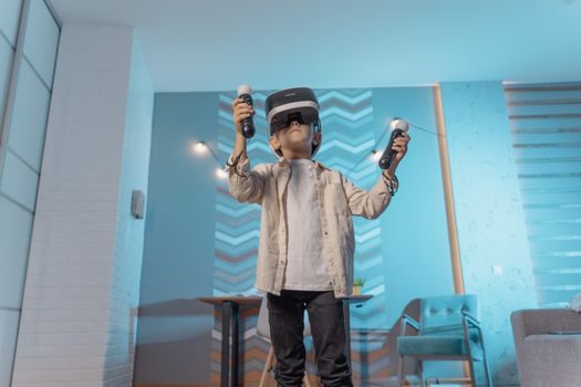 A young boy experiencing virtual reality gaming with VR goggles and controllers indoors.