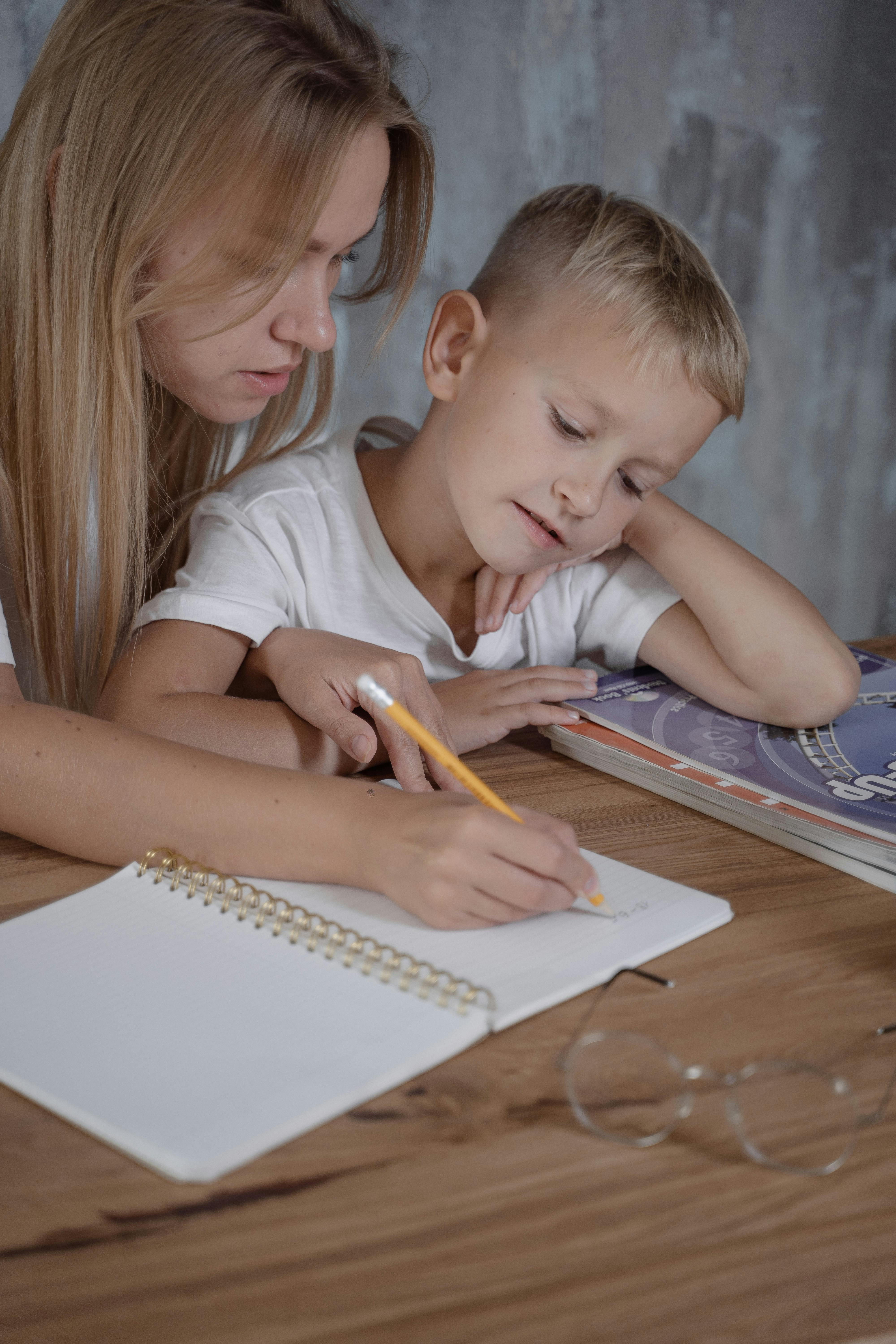 a boy looking at the handwritten of the w0oman sitting beside him