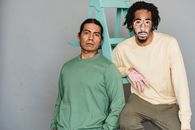 两个穿着时尚服装的男人在工作室背景下用梯子摆出不同的姿势