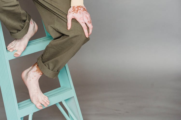 Crop Man Sitting On Ladder In Modern Studio