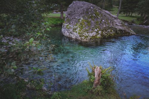 Free Rippling water surface of lake with big stone in green park with trees Stock Photo