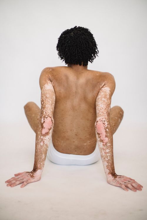 Free Back view of unrecognizable African American male in underwear leaning on hands while sitting against white background Stock Photo