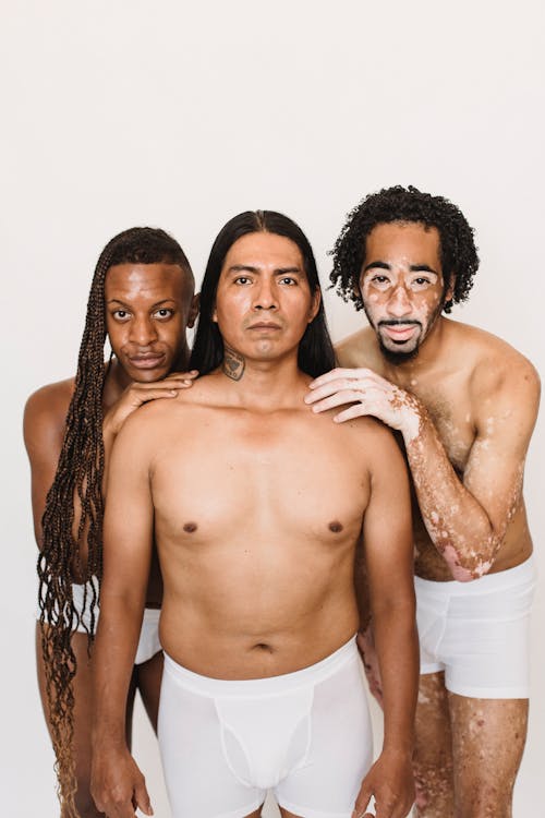 Multiethnic men embracing against white background