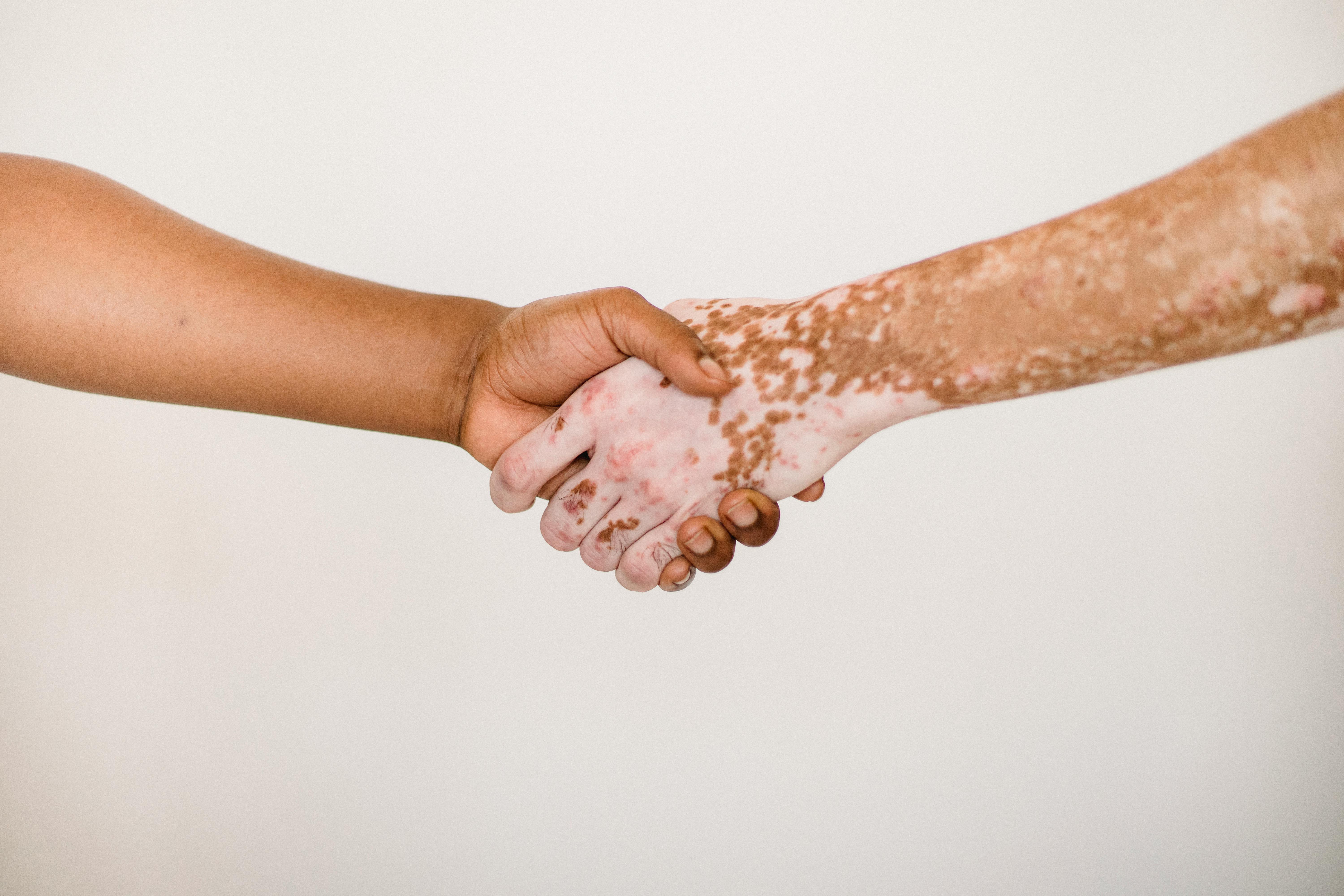 crop faceless men shaking hands in studio