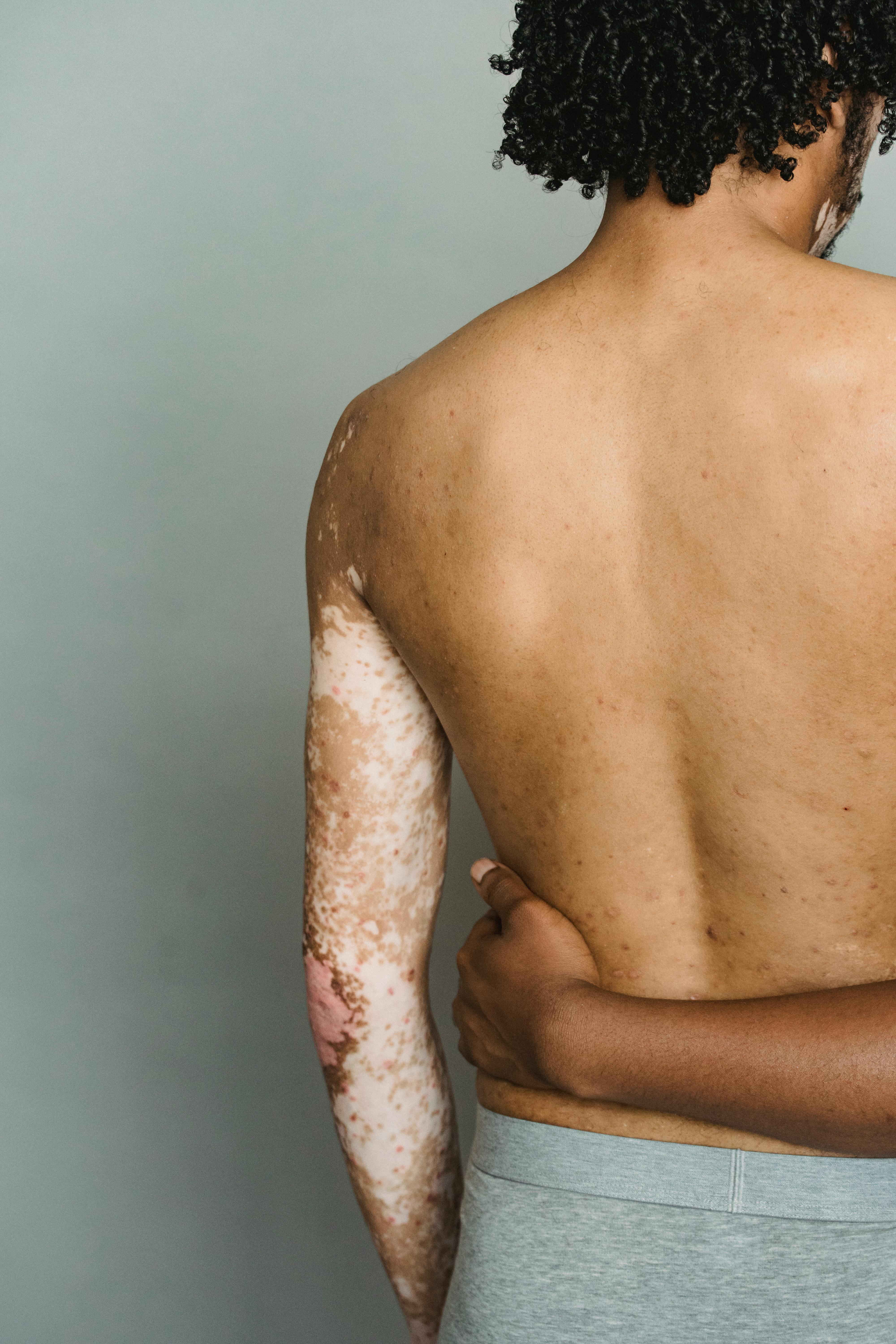 crop anonymous shirtless men embracing in studio