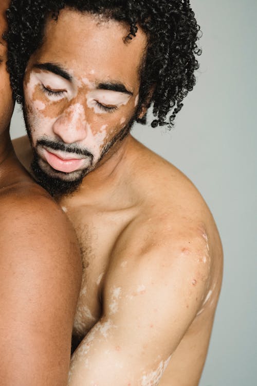 Crop shirtless man with eyes closed embracing boyfriend