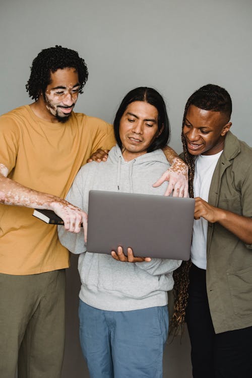 Multiethnic coworkers using laptop together in studio
