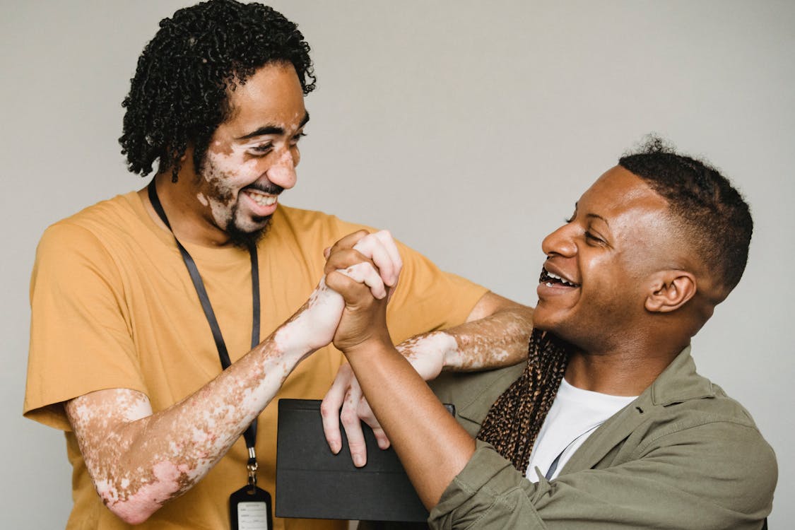 Free Laughing black male colleagues clasping hands in excitement together Stock Photo
