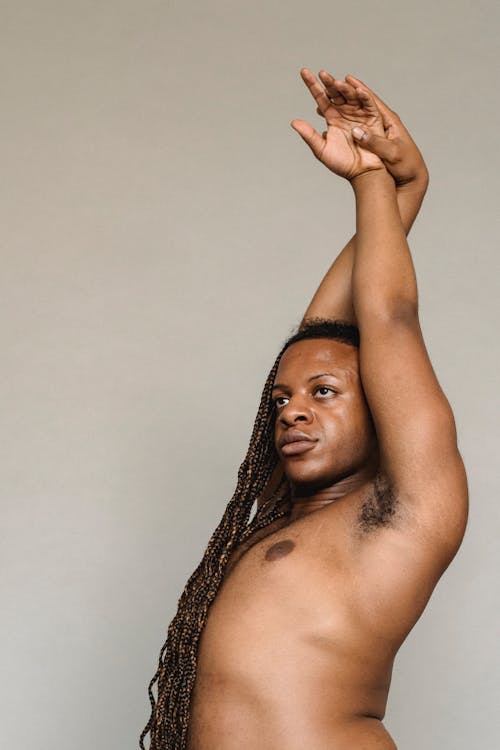 Гомосексуальный черный мужчина без рубашки, поднимающий руки