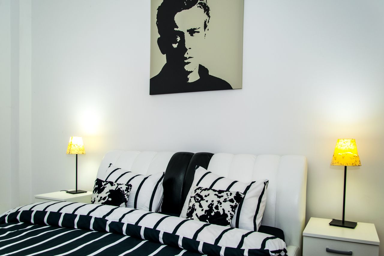 Bedroom with a black-and-white headboard, white nightstands, and matching table lamps
