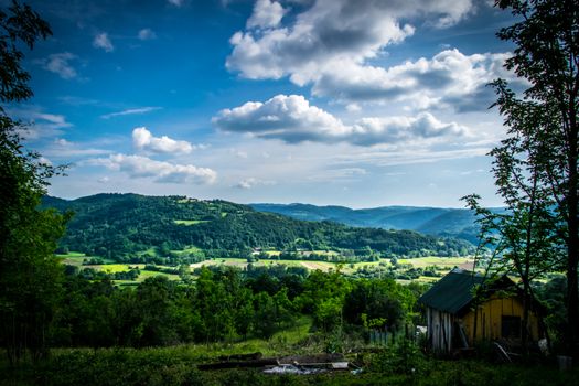 A picturesque countryside landscape featuring lush green hills under a bright blue sky.