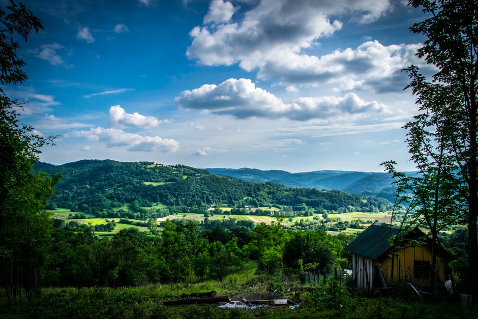 A picturesque countryside landscape featuring lush green hills under a bright blue sky.