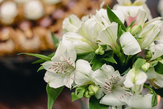Delicate elegant bouquet with tender white Peruvian lily flowers placed on table before wedding celebration