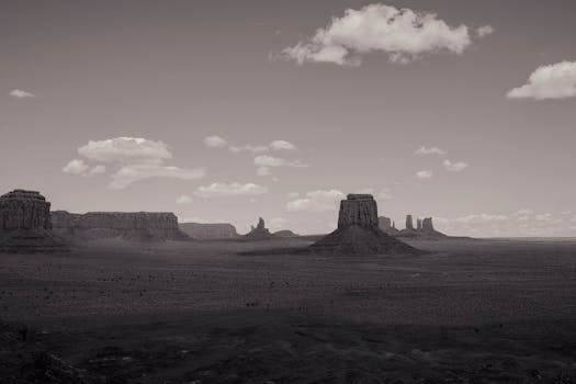 Black and white view of Monument Valley's iconic rock formations under a vast sky.