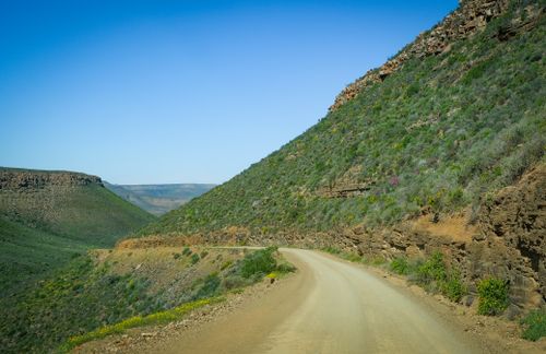 Free Winding dirt road in lush hilly landscape under a clear blue sky in South Africa. Stock Photo
