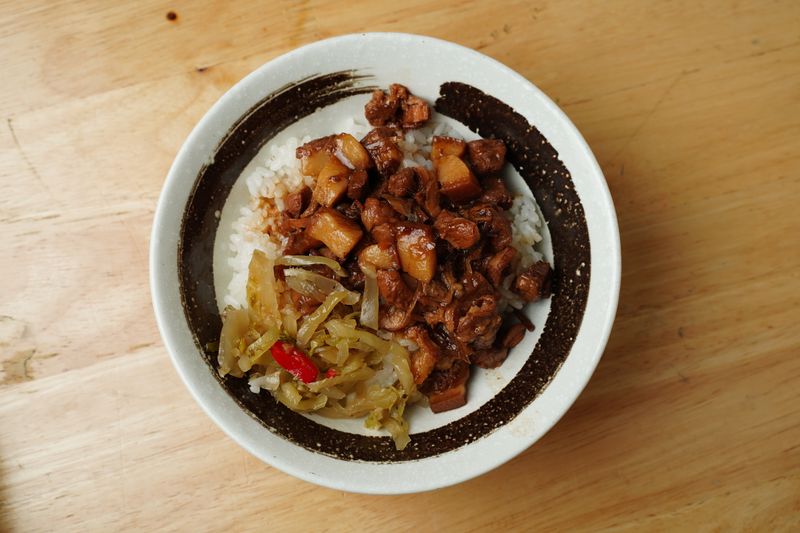Braised pork over rice with pickled vegetables in a stoneware bowl — photo by Kai-Chieh Chan on Pexels