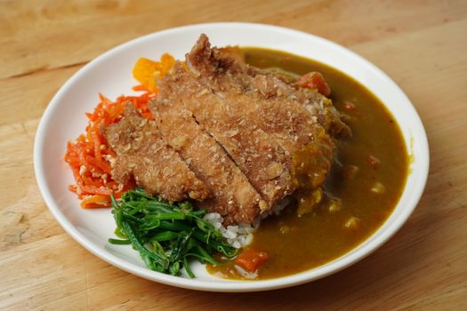 Delicious plate of pork cutlet with Japanese curry, rice, pickled vegetables, and greens.