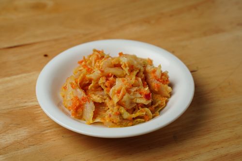 Free Savory Korean kimchi served in a classic white ceramic bowl on a wooden table. Stock Photo