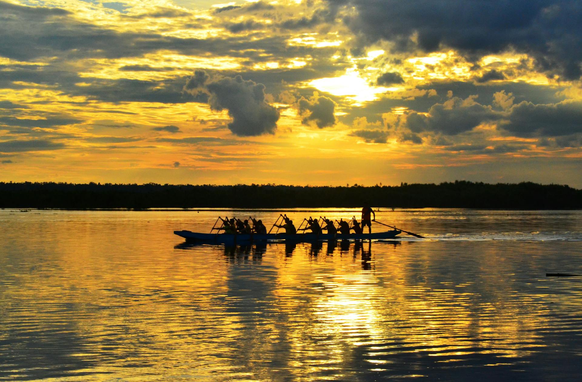 A rowing team paddling on a serene lake during a vibrant sunset, reflecting teamwork and nature's beauty.