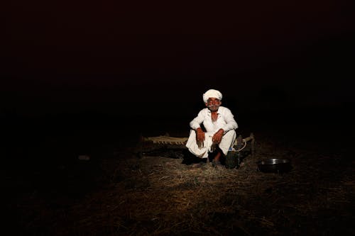 Man in White Dress Shirt and Black Pants Sitting on Brown Dried Grass