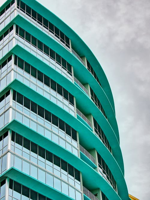 Green Concrete Building with Glass Windows Under White Sky