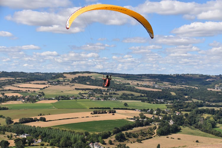 Person Parachuting Above Green Grass Field